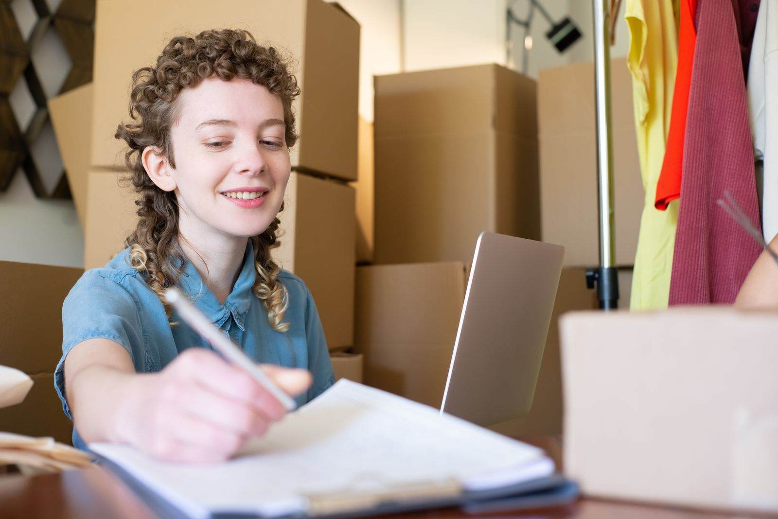 Small business owner working on a laptop surrounded by stock and packages
